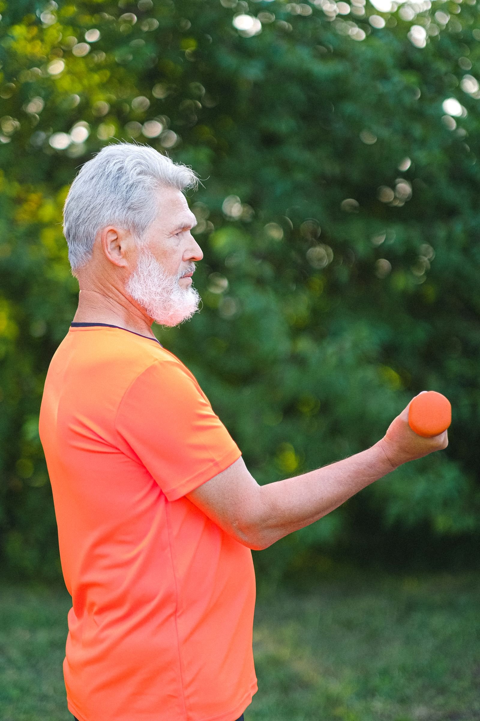Homme âgé pratiquant un exercice de renforcement musculaire avec des haltères